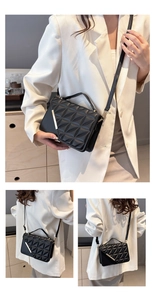 Detail shot of black quilted shoulder bag with gold metal trim and adjustable strap