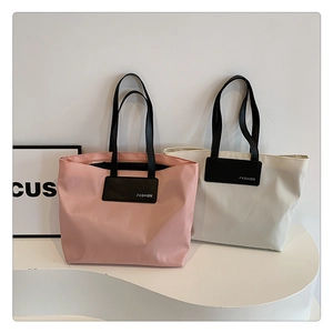 Macro detail of high-capacity nylon tote bags in pink and beige with leather fashion logo