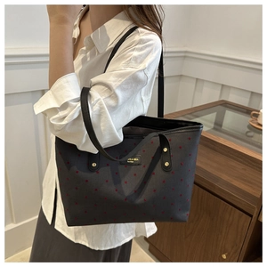 Detail of black canvas tote bag with red polka dots and slim leather shoulder straps