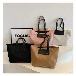 Detail of four colorful nylon tote bags with faux leather handles on a minimal display stand