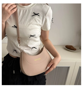 Gros plan du sac demi-lune beige avec logo et bandoulière en cuir réglable et amovible