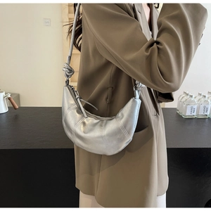 Detail of silver crescent shoulder bag featuring stylish knot and metallic texture