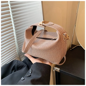 Detail of a brown woven texture trapezoid handbag with gold-tone hardware and strap