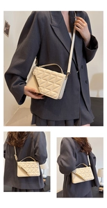 Detailed view of beige quilted handbag with gold bar accent and adjustable strap