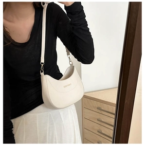 Mannequin portant un sac croissant blanc crème avec logo doré et fine bandoulière