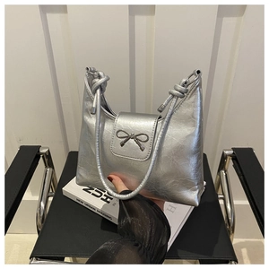 Detail of silver textured shoulder bag featuring metal bow and chunky knot handle