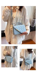 Detail of light blue quilted crossbody bag with gold metallic trim and thin strap