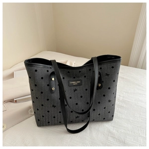 Detail of star print denim tote bag with leather straps and central logo patch
