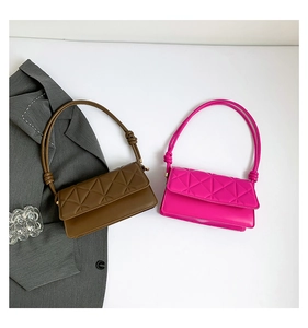 Flat lay view of geometric quilted leather shoulder bags in brown and magenta with knotted straps