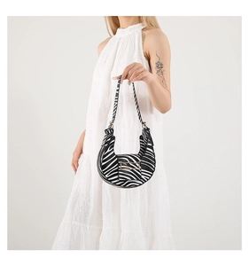Detailed macro view of zebra print crescent shoulder bag with smooth fabric texture