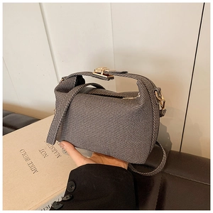 Detailed close-up of a grey twill crossbody bag featuring a shiny gold metal lock