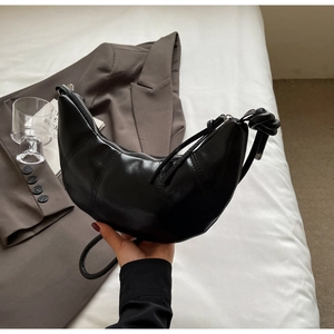 Detailed view of the knotted shoulder strap and smooth black leather on this hobo bag