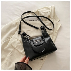 Detail of black PU leather handbag featuring silver bow and knot handle design