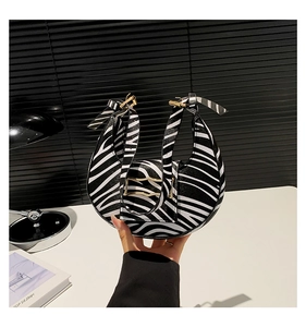 Detail of zebra print crescent bag featuring a bow handle and elegant gold buckle