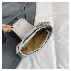 Detailed interior of silver patent leather shoulder bag with zipper pocket and lining