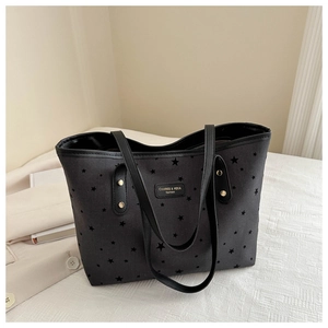 Detail of star-patterned black tote bag featuring metallic rivets and brand label