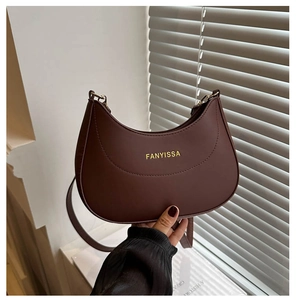 Détail d'un sac demi-lune marron foncé avec logo doré et texture en cuir élégante
