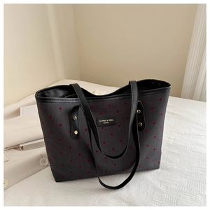 Canvas tote bag with red polka dots and leather straps placed on a white bed