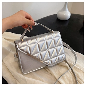 Close-up of silver handbag featuring triangular quilted texture and metal trim details