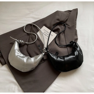 Detailed view of quilted croissant bags in silver and black on a brown blazer