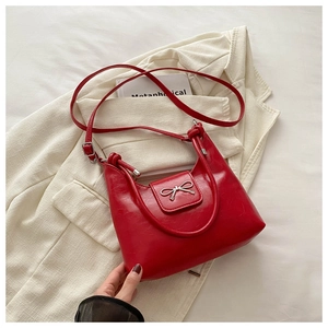 Close-up of red PU leather bag featuring a silver bow buckle and knotted handle detail