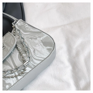 Detailed close-up of metallic silver underarm bag with unique marble texture and chain
