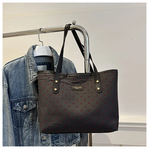 Close-up of black tote bag with red heart embroidery and golden rivet details