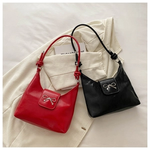 Detailed close-up of glossy hobo bags in red and black with bow metal buckles