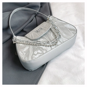 Detail of silver underarm bag with marble texture, butterfly buckle and metal chains