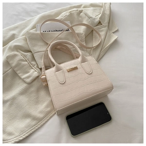 Gros plan de la texture pierre sur le petit sac cabas beige avec détails métalliques