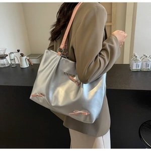 Silver tote bag with pink bow and heart charm detail on stylish leather shoulder strap