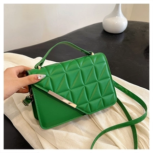 Close-up of green quilted faux leather handbag with triangle stitching and gold metal trim
