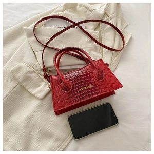 Detail of red crocodile texture PU leather handbag with gold logo and long shoulder strap