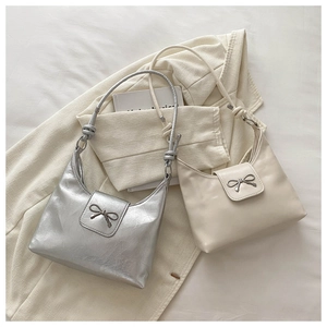 Detail of silver metallic and cream leather handbags with decorative bow knots