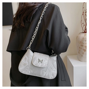 Detail of silver marble shoulder bag featuring metallic butterfly buckle and chunky chain