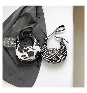 Detail of crescent shoulder bags in animal prints with golden buckles and slim straps