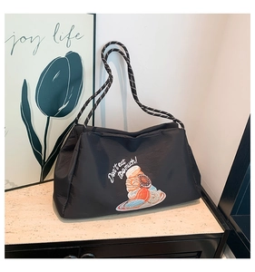 Gros plan du sac cabas matelassé noir avec motif de donuts et sangle tressée