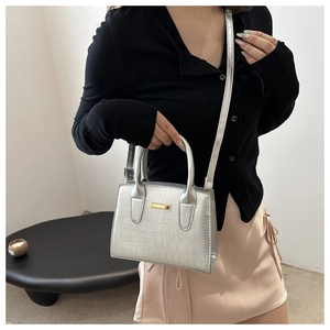 Sac à main argenté à texture crocodile avec plaque métal porté en bandoulière