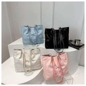 Detailansicht großer Tragetaschen in Blau, Schwarz, Creme und Rosa mit Schleifenband
