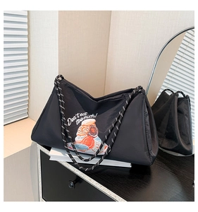 Détail d'un sac cabas noir matelassé avec broderie donut et poignée en corde épaisse