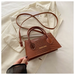 Macro detail of brown crocodile embossed texture and golden stamp on the handbag