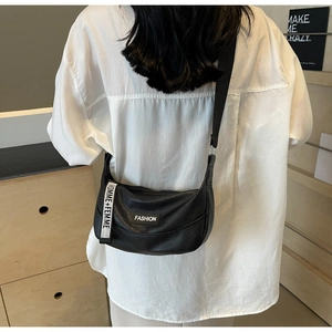 Close-up of black lychee leather crossbody saddle bag with fashion logo and woven strap