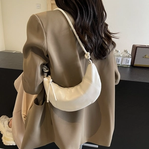 Minimalist white croissant shoulder bag with pleated details on a stylish model