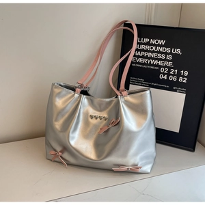 Detail of silver metallic tote bag featuring pink ribbons and heart-shaped metal studs