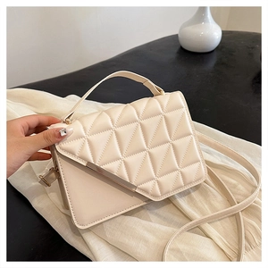 Close-up of beige quilted crossbody bag with golden metal trim and sleek top handle