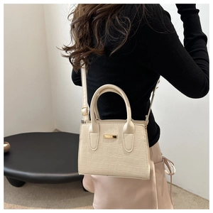 Détail du sac à main crème gaufré crocodile avec plaque dorée et bandoulière réglable