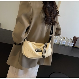 Detail showing cream half-moon bag with pebbled texture and fashion brand tags