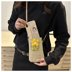 Close-up of woven straw phone bag with a yellow floral accent and adjustable strap