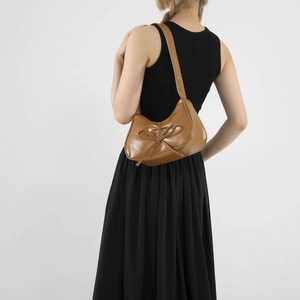 Französische braune Leder-Halbmondtasche mit Schleife, getragen von einem Model