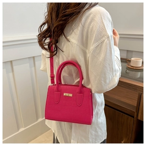 Détail du sac à main rouge rose avec motif crocodile porté par un mannequin en salle